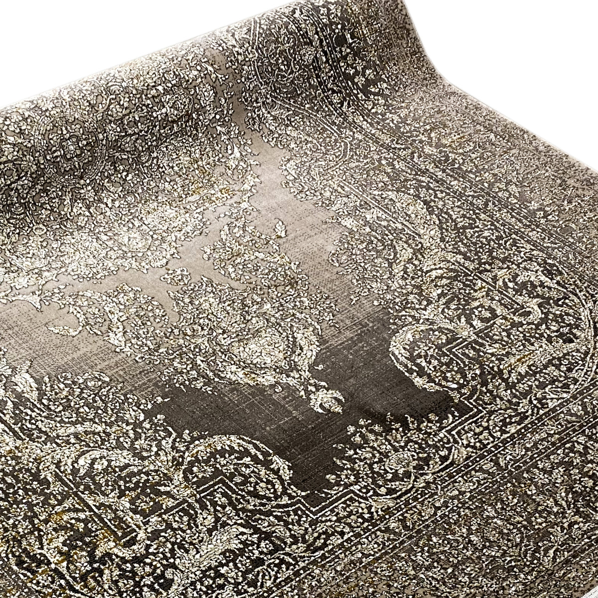 Superficie de alfombra con un gran motivo ornamental en beige y gris oscuro, primer plano