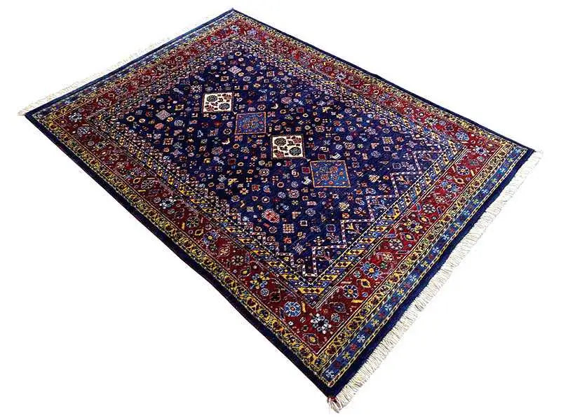 Alfombra oriental azul oscuro en diagonal, con marco rojo y motivos de medallones