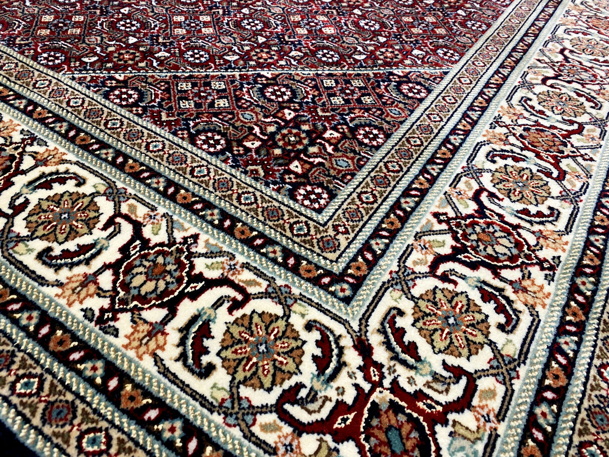 Alfombra con diseño ornamental, base oscura en tonos rojos, azules y crema