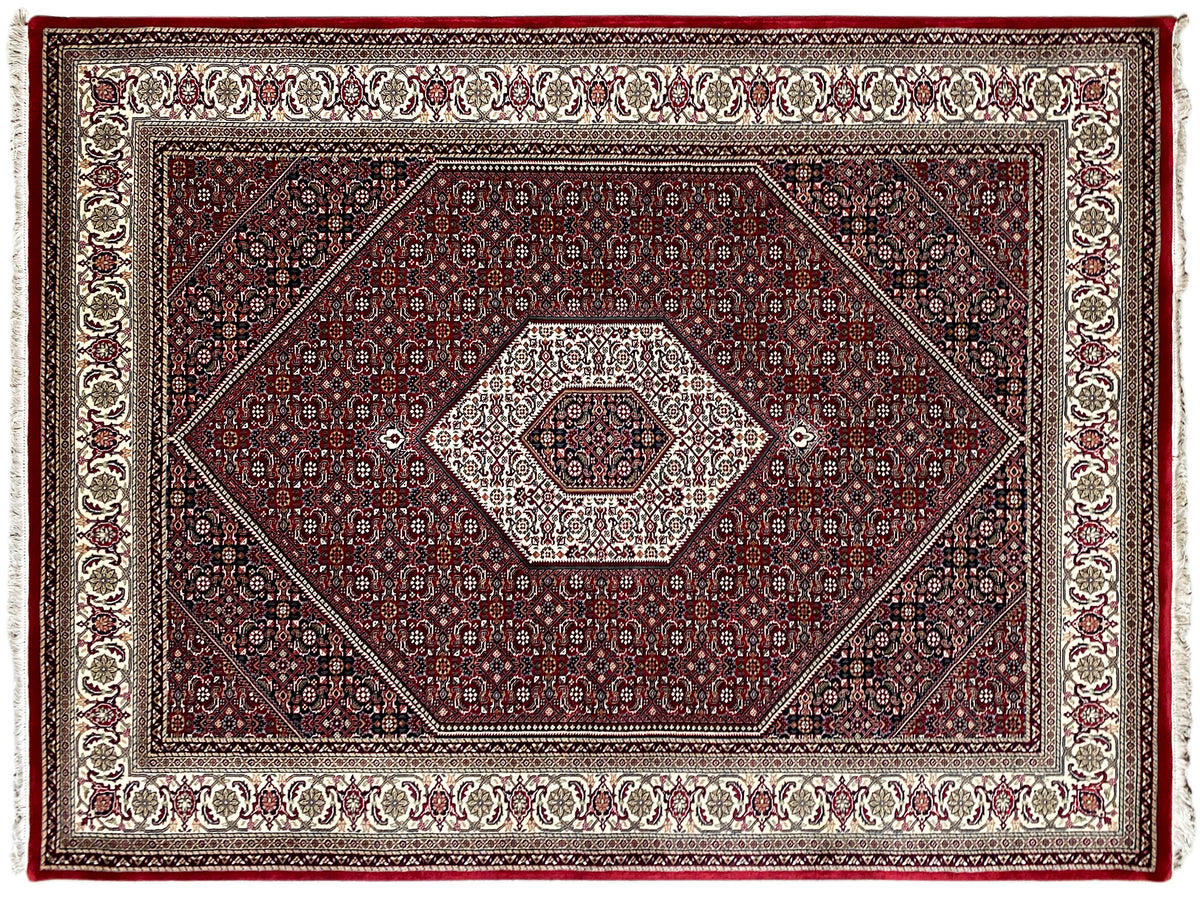 Alfombra roja de Bidjar con diseño geométrico y cenefa en crema y azul oscuro