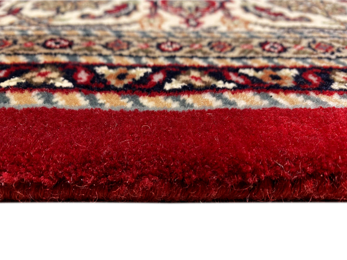Alfombra marrón rojiza con pelo denso y cenefa multicolor en el borde