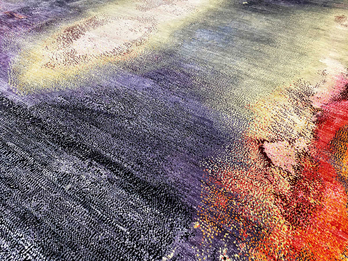 Alfombra de diseño con un patrón abstracto en lila, azul, crema y naranja; textura de pelo largo.