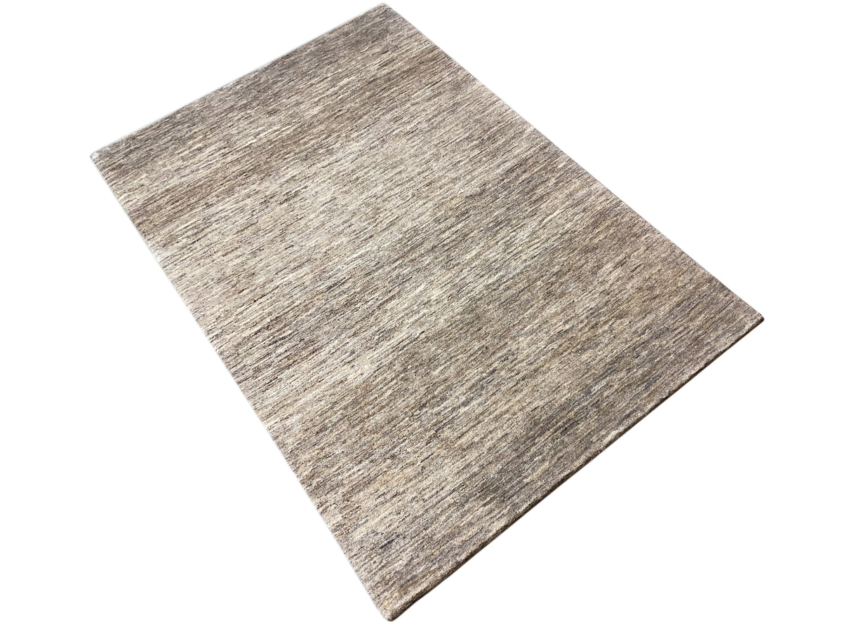 Alfombra Gabbeh rectangular, colocada ligeramente en diagonal, mezcla de gris y beige con una textura fina
