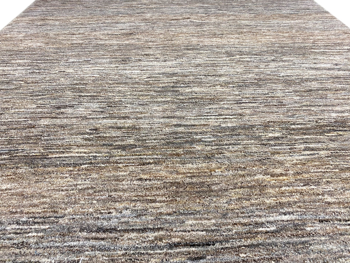 Primer plano: alfombra de 243x168 con diseño lineal gris-marrón jaspeado y fina estructura de pelo.