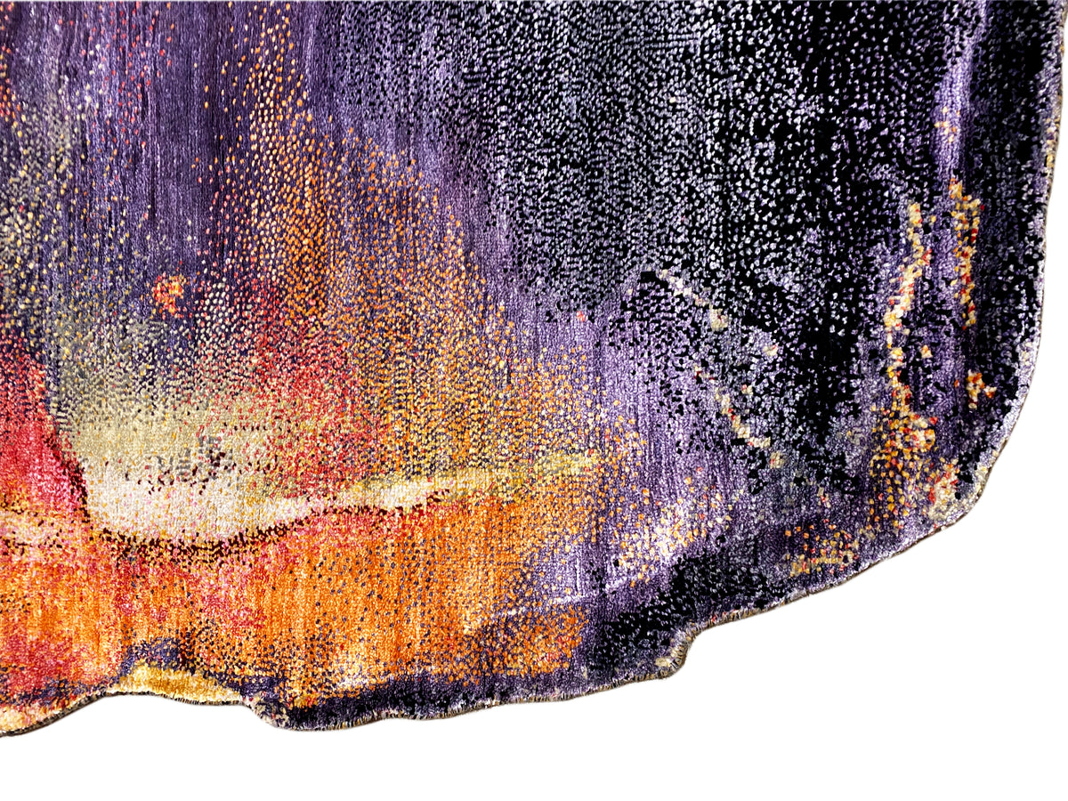 Vista cercana de una alfombra de diseño: textura tejida granulada con acentos lilas, naranjas y crema.