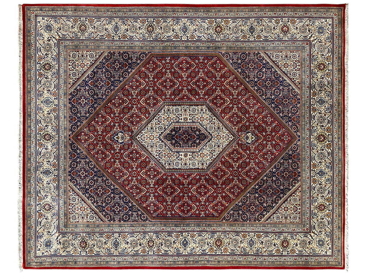 Alfombra con campo interior rojo, medallón claro y cenefa decorativa enmarcada