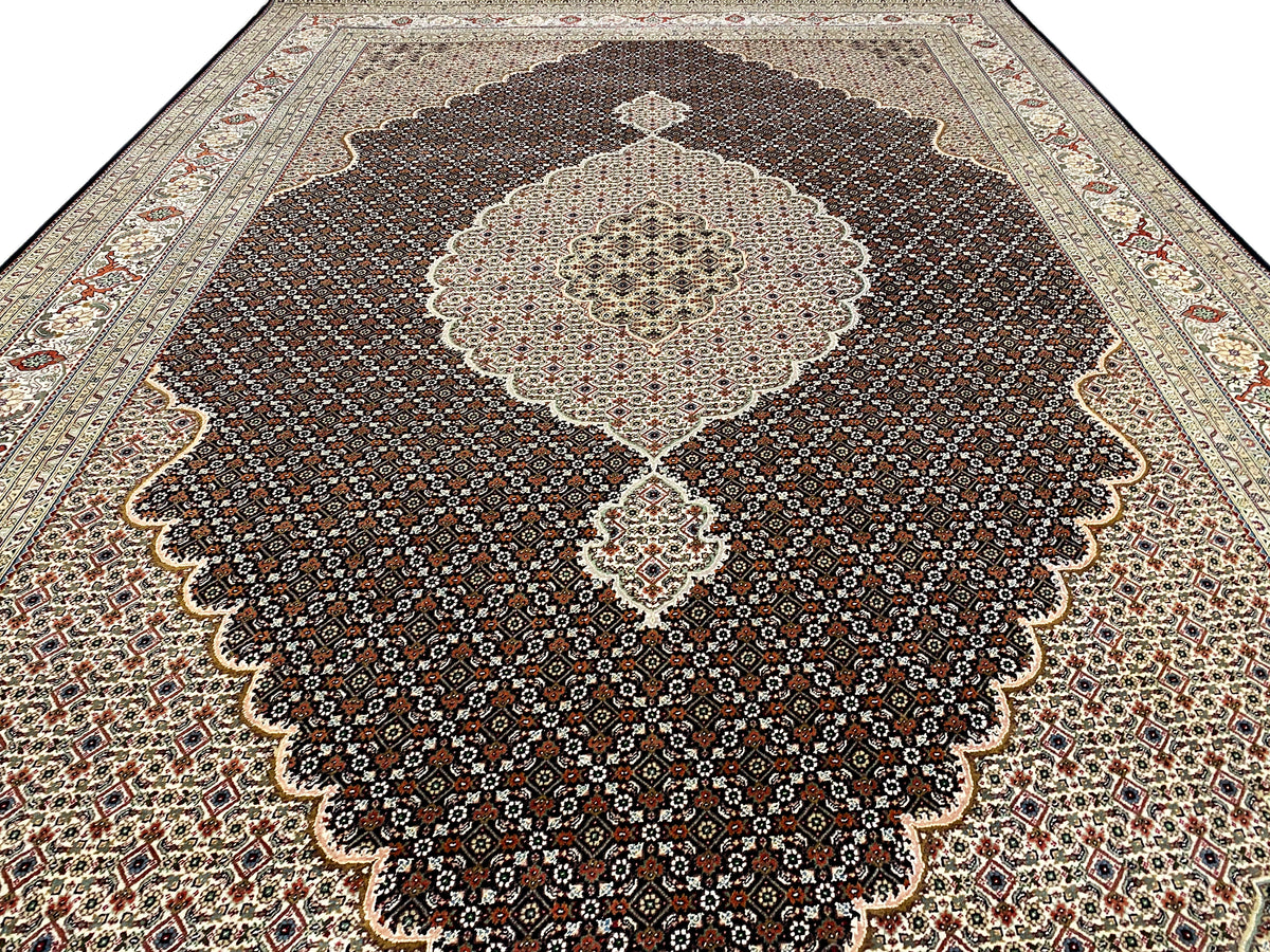 Alfombra marrón oscuro con un gran medallón en forma de flor y una cenefa ornamental