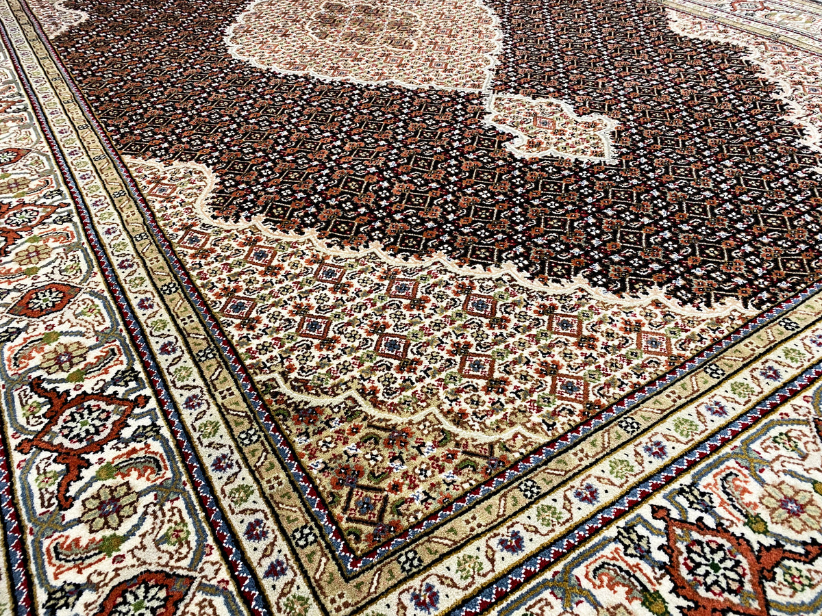 Primer plano de una alfombra Indo-Tabriz marrón: ornamentos del borde y oscuro motivo floral
