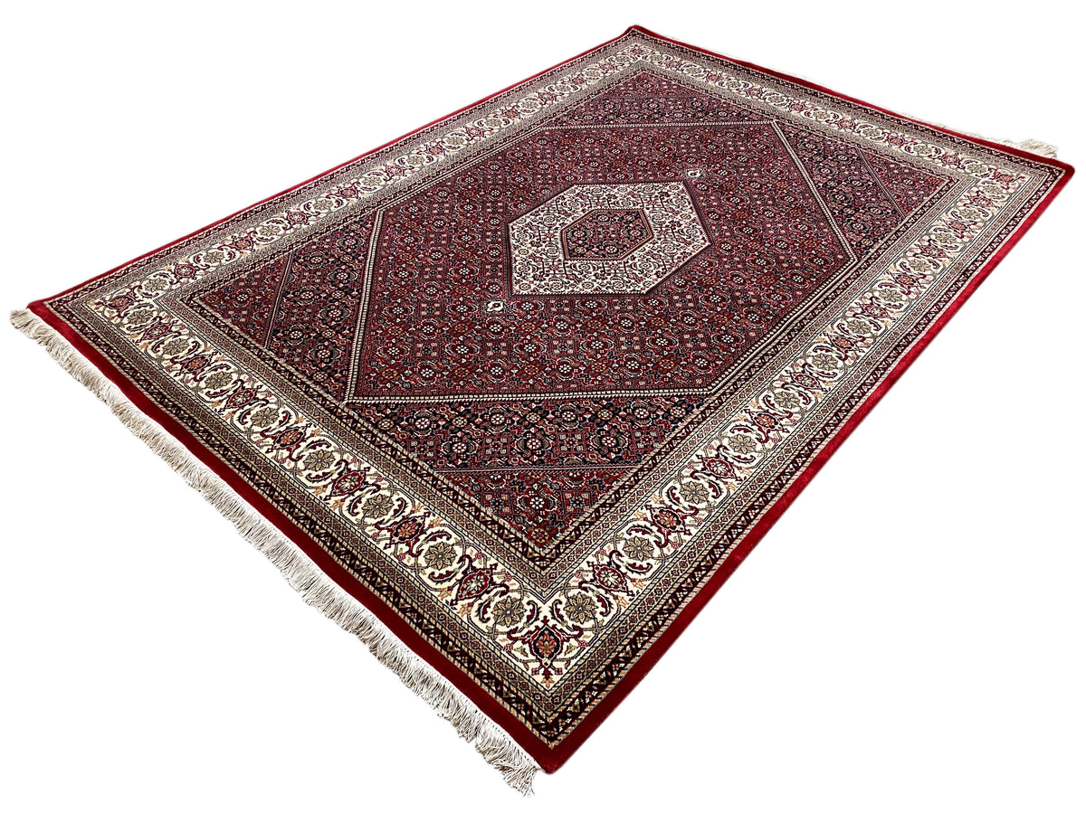 Alfombra Bidjar roja con un diseño simétrico y flecos en el borde
