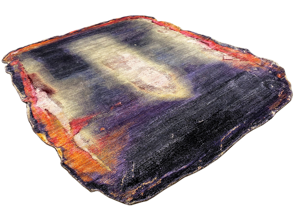 Alfombra de diseño de forma irregular con un juego abstracto de colores en azul oscuro, morado, crema y naranja.