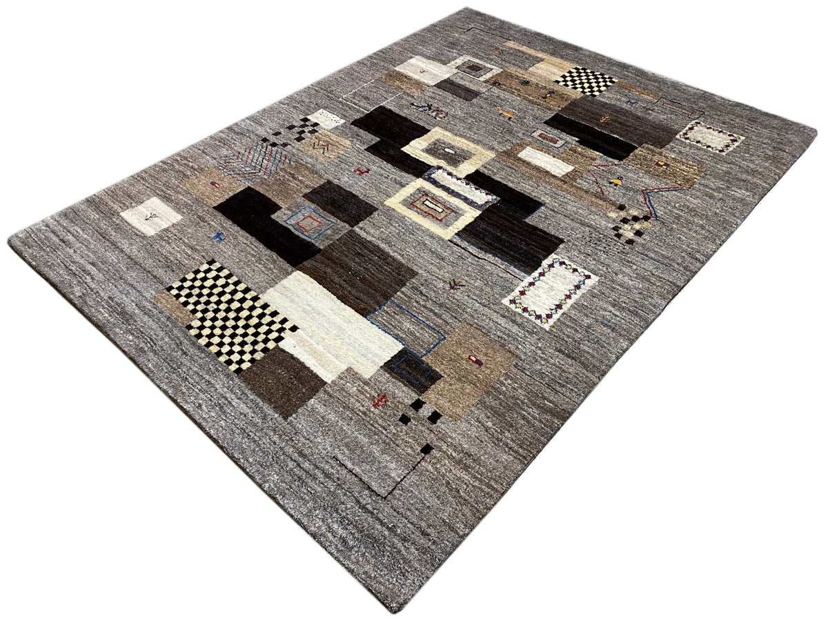 Alfombra Gabbeh de 235x171 cm, presentada en diagonal: motivos de patchwork en gris y marrón oscuro