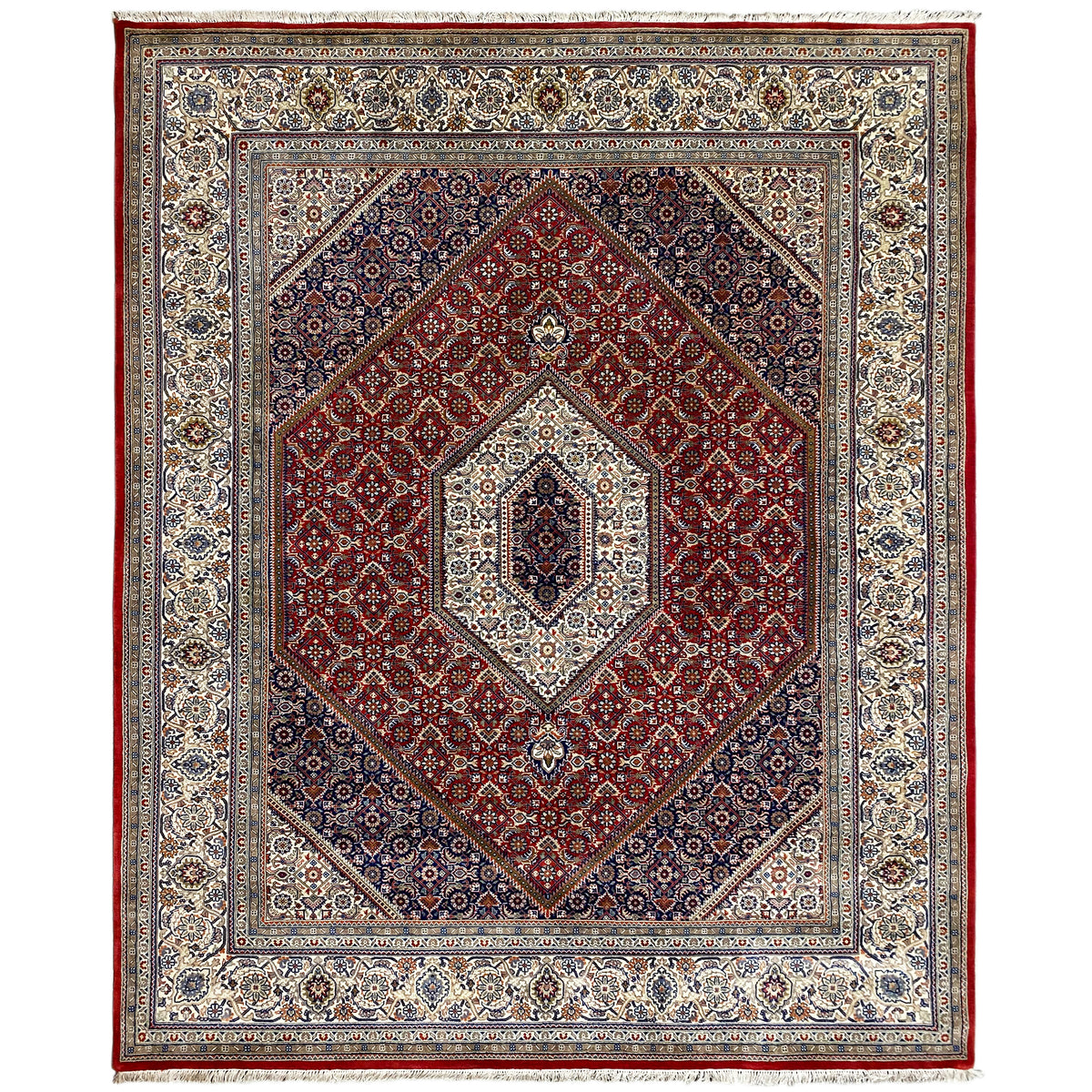 Alfombra Bidjar con medallón rojo y ornamentos azules y blancos en un marco de cenefa