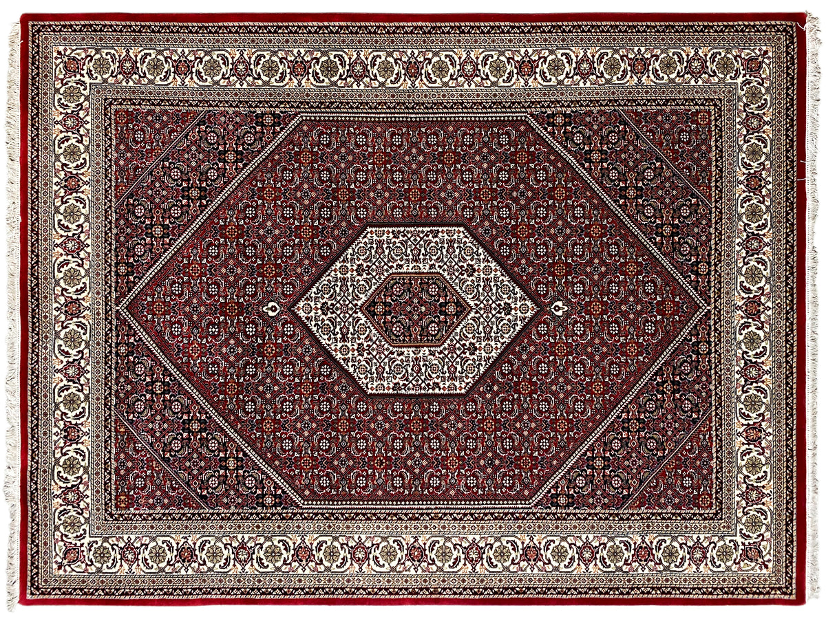 Vista de cerca de la alfombra roja: motivos de rombos y ornamentos con cenefa decorativa, flecos
