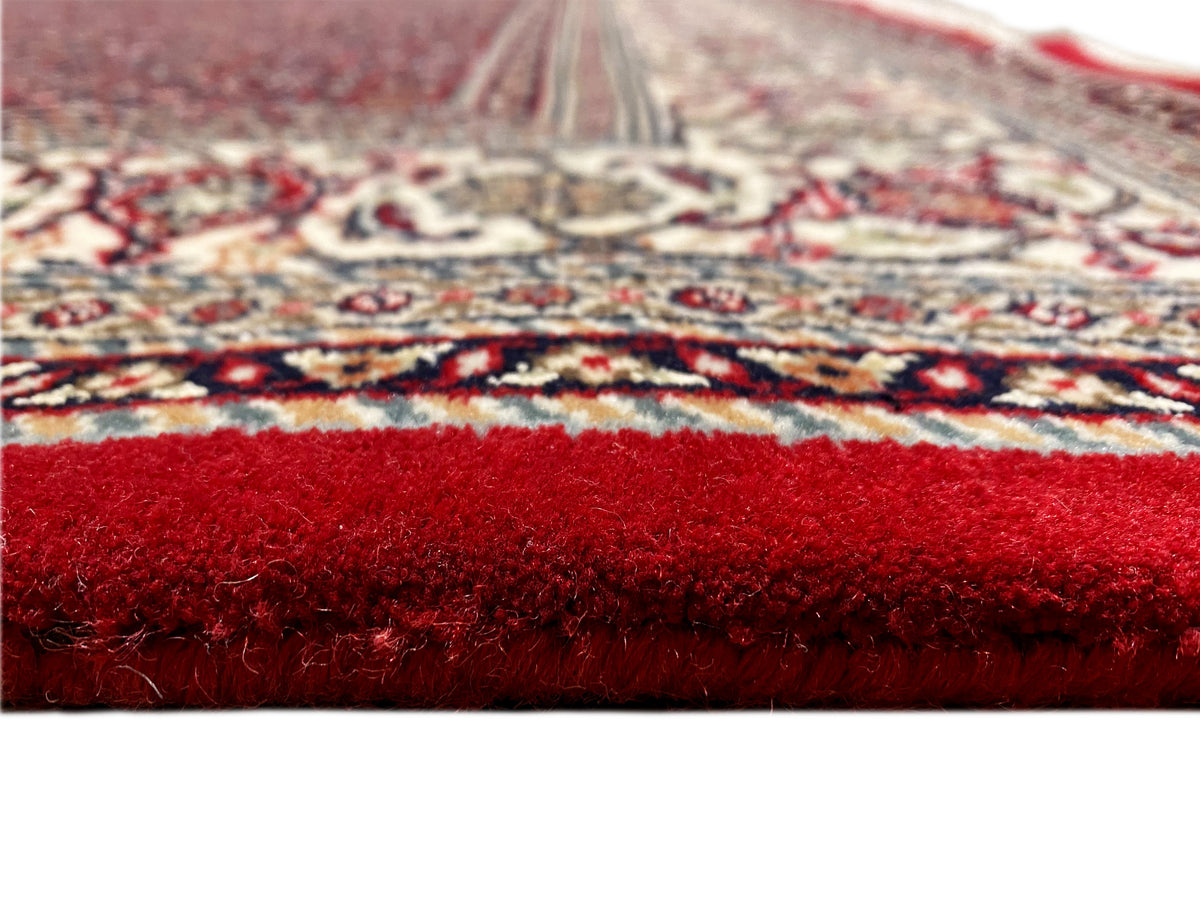 Primer plano de la superficie de la alfombra: pelo rojo y cenefa estampada en el borde