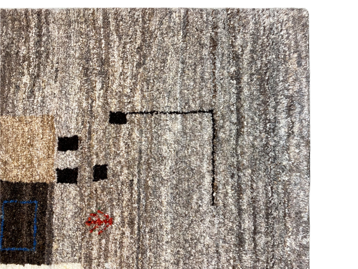Primer plano del pelo de una alfombra Gabbeh en gris beige claro con un patrón de líneas