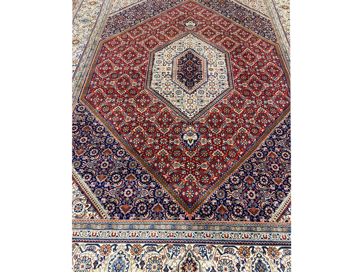 Vista de cerca: medallón rojo sobre fondo azul oscuro, con esquinas decorativas blancas y cenefa inferior