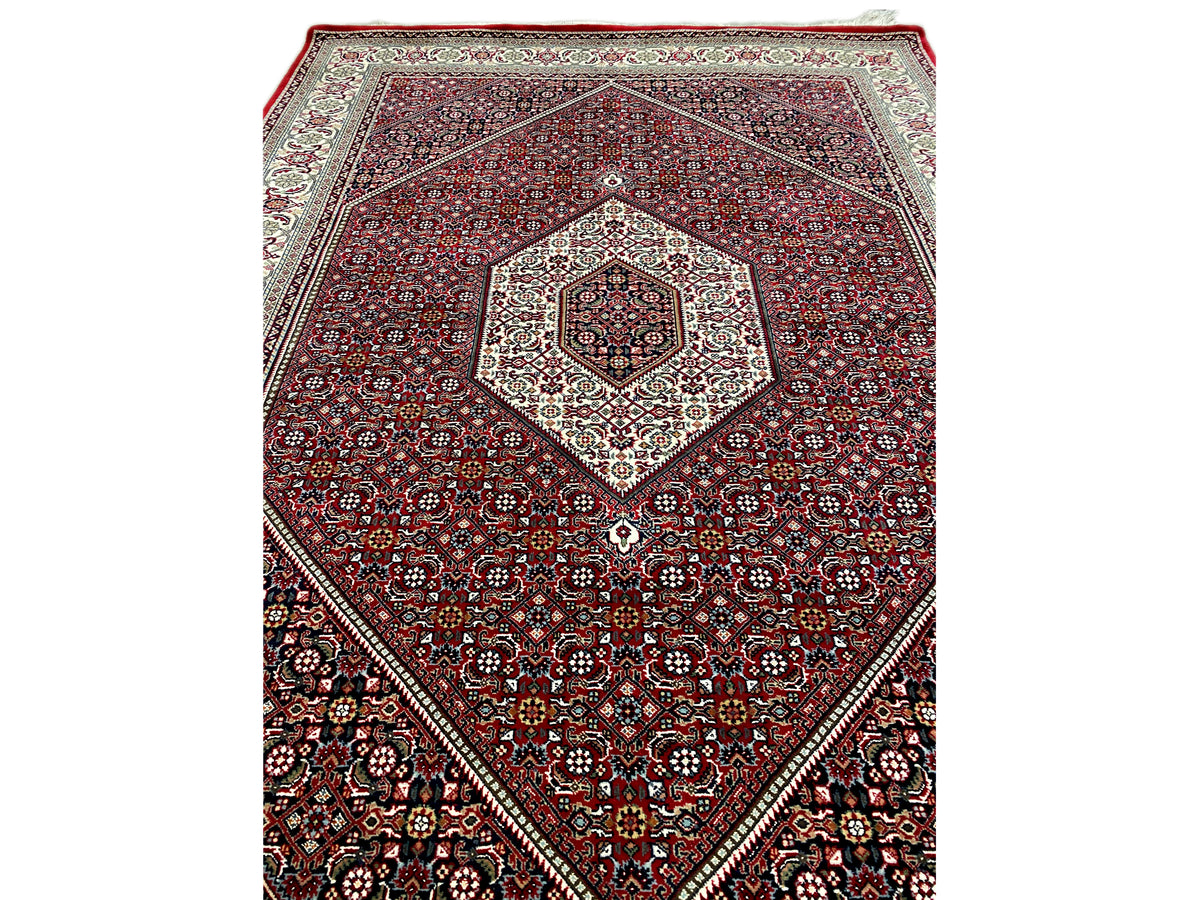 Alfombra roja con medallón de diamante y ornamentación de pequeños motivos en crema y azul oscuro
