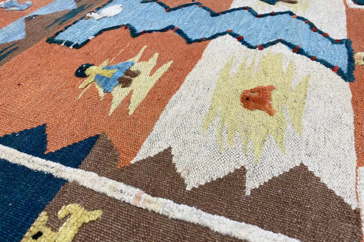 Detalle de alfombra kilim con motivos florales y zigzag en marrón, azul y crema