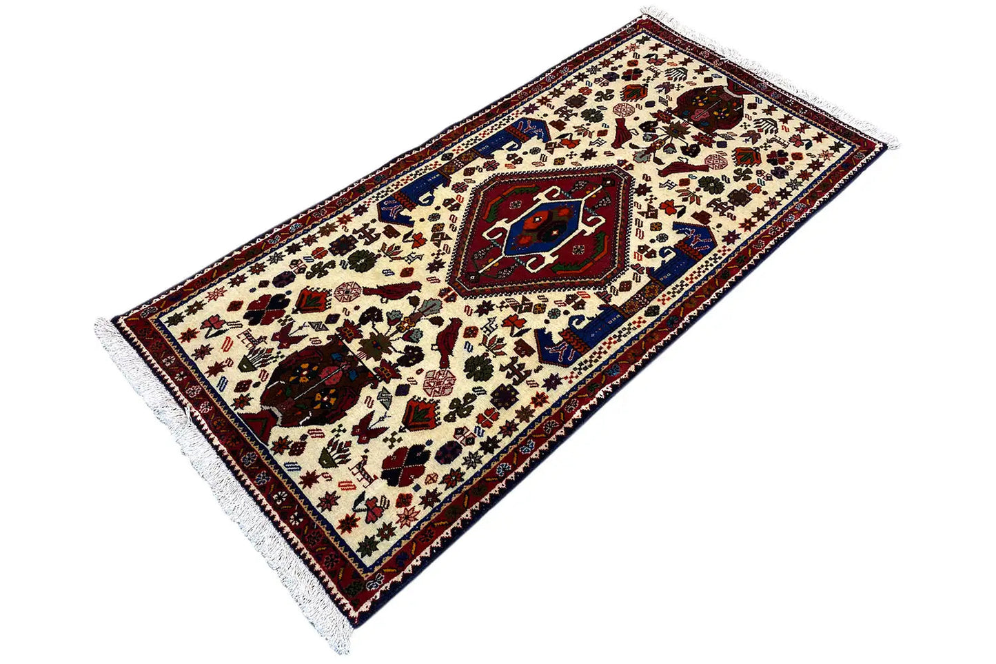 Alfombra oriental, patrón de color crema con bordes azules y rojos, flecos, vista alargada