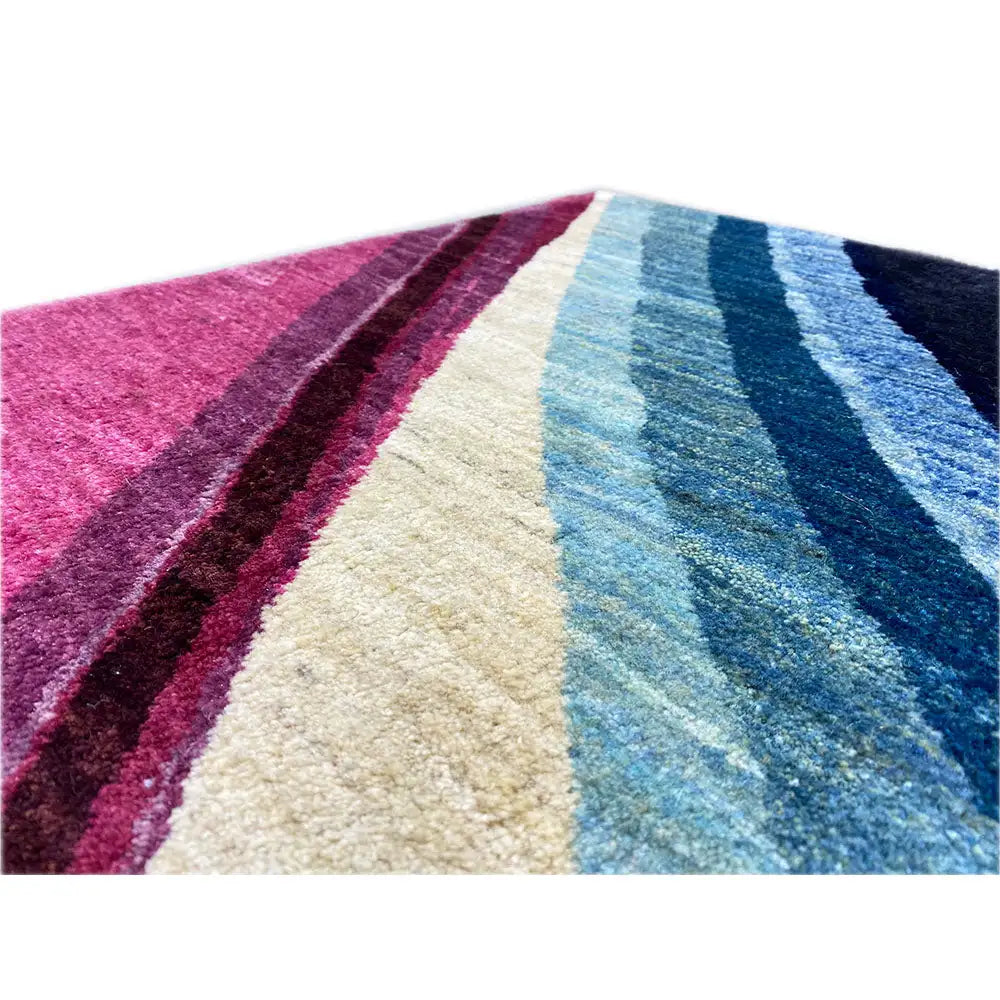 Detalle de alfombra Gabbeh con franjas diagonales en rosa, crema y azul
