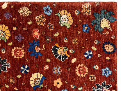 Teppich-Detailaufnahme: dichter Flor mit rötlich-braunem Grund und bunten Blumenmotiven.