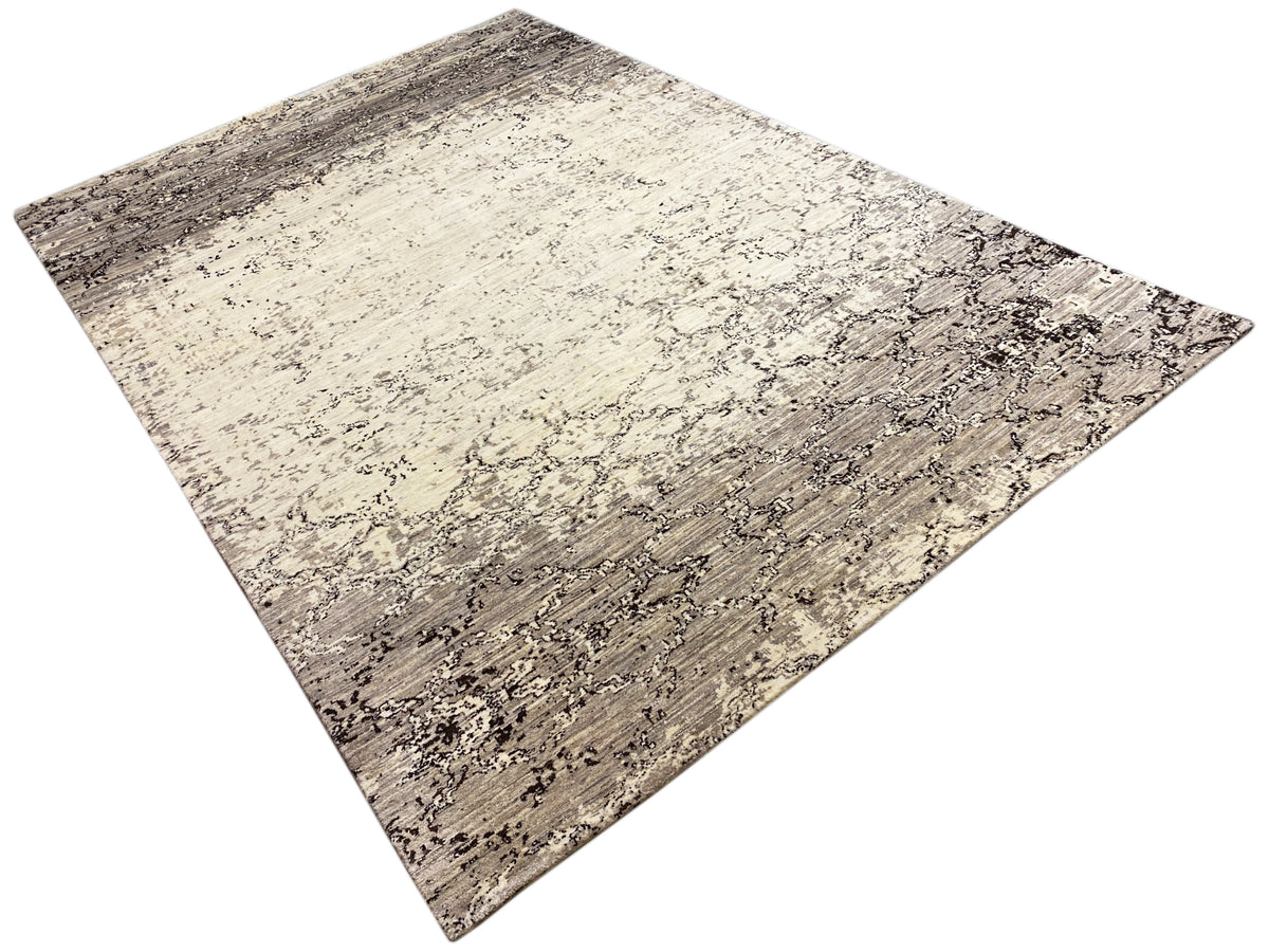 Alfombra dispuesta en diagonal en beige y gris oscuro con un patrón abstracto