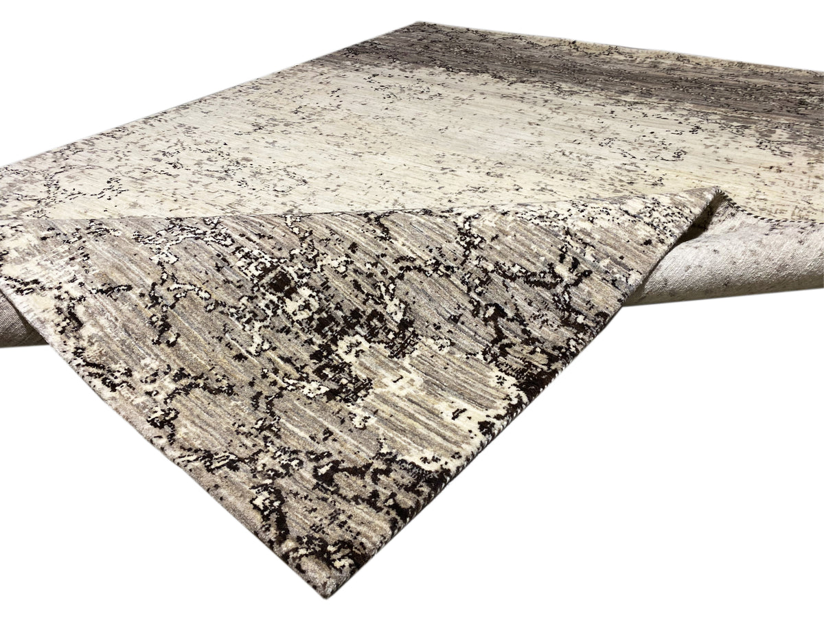 Alfombra colocada en diagonal, con fondo beige claro y líneas ornamentales gris oscuro