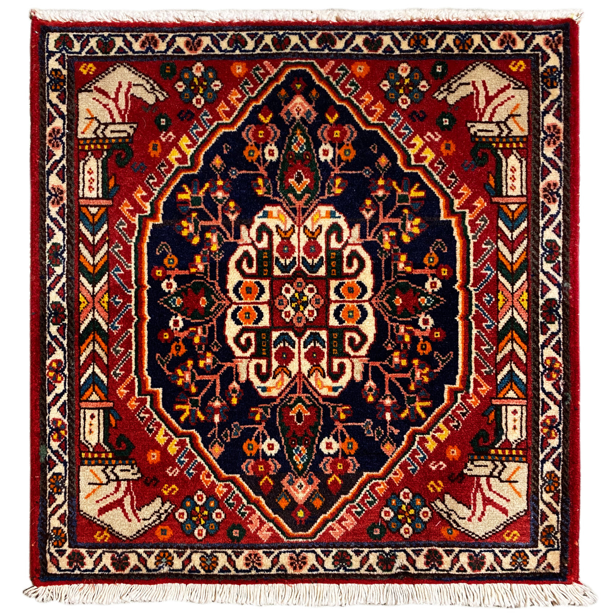 Quadratischer Teppich mit dunkelblauem Grund und rotem Rautenmuster, Fransen an den Ecken