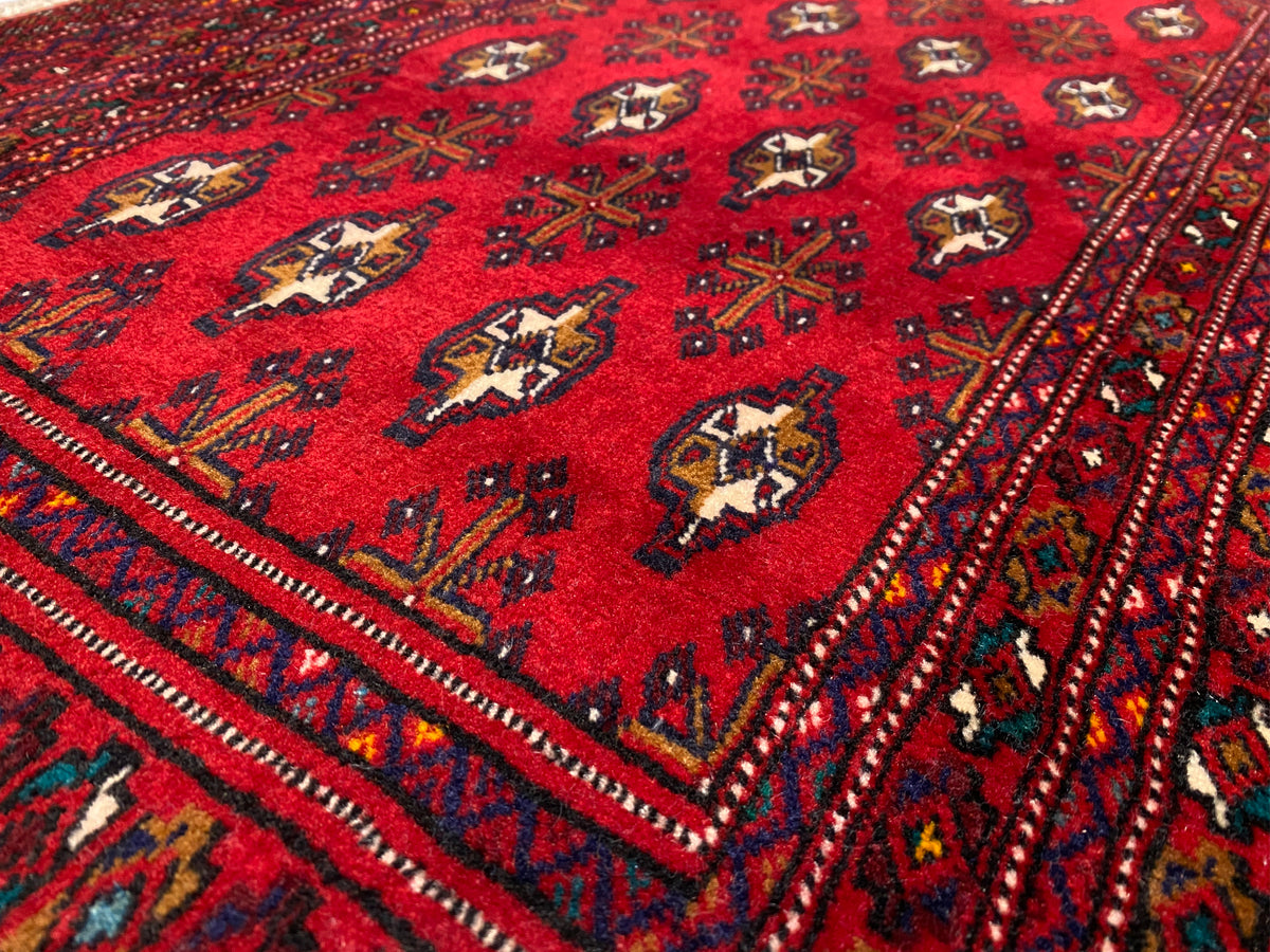 Nahaufnahme Turkmen Teppich: rotes Gewebe mit Medaillon-Motiven in dunkler Bordüre