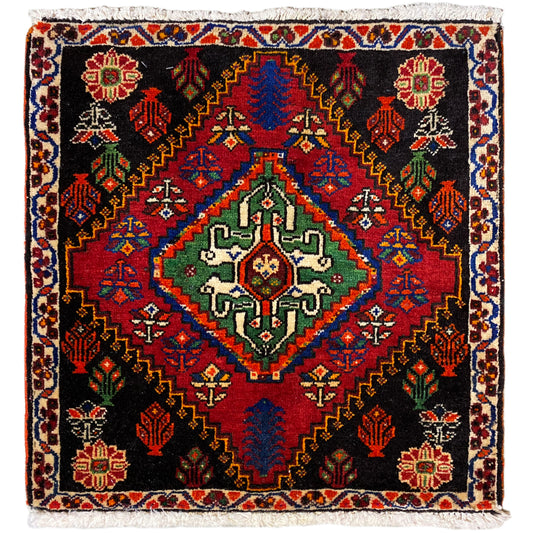 Alfombra Poshti de 56x56 cm con fondo negro, adornos de colores y flecos decorativos
