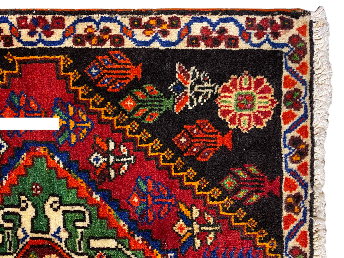 Alfombra Poshti de 56x56 cm en primer plano: cenefa ornamental con rombos de colores sobre fondo negro