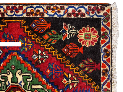 Alfombra Poshti de 56x56 cm en primer plano: cenefa ornamental con rombos de colores sobre fondo negro