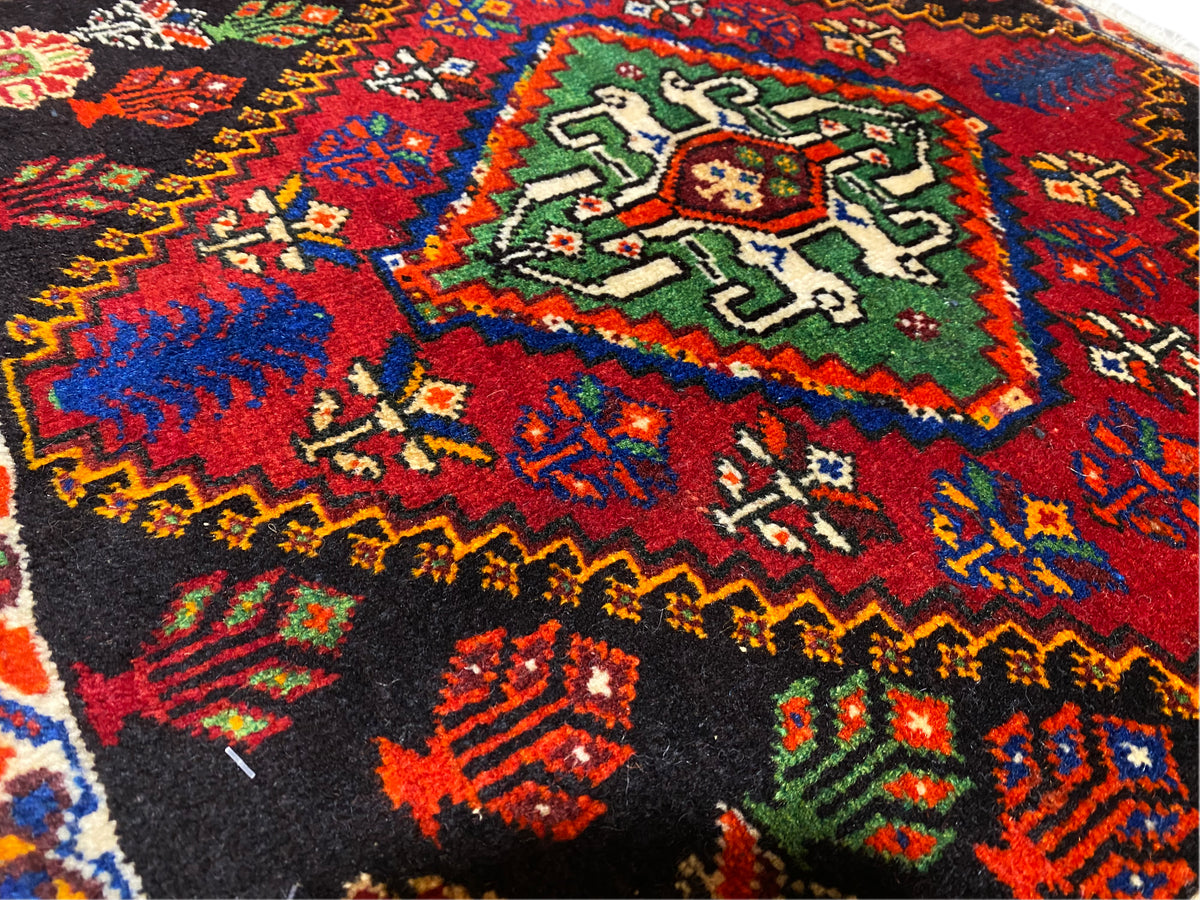 Alfombra Poshti de 56x56 cm, vista cercana del campo central con ornamentos verdes y rojos
