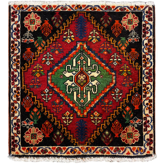 Alfombra Poshti, cuadrada: alfombra tejida negra con un motivo decorativo rojo, verde y azul