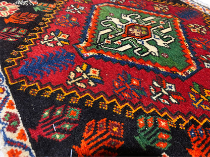 Vista detallada de una esquina de una alfombra Poshti: adornos geométricos multicolores sobre fondo negro