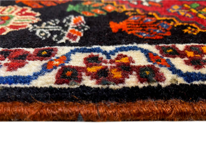 Detalle del borde de una alfombra Poshti: cenefa multicolor y pelo de la alfombra en el remate inferior
