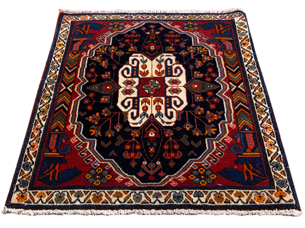 Alfombra Poshti rectangular con fondo azul y un patrón ornamental simétrico