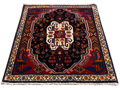 Alfombra Poshti rectangular con fondo azul y un patrón ornamental simétrico