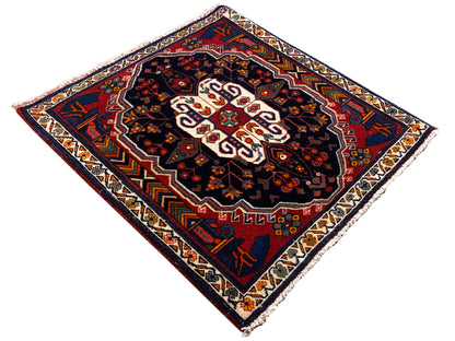 Alfombra Poshti con diseño de rombos, fondo oscuro y ornamento central blanco