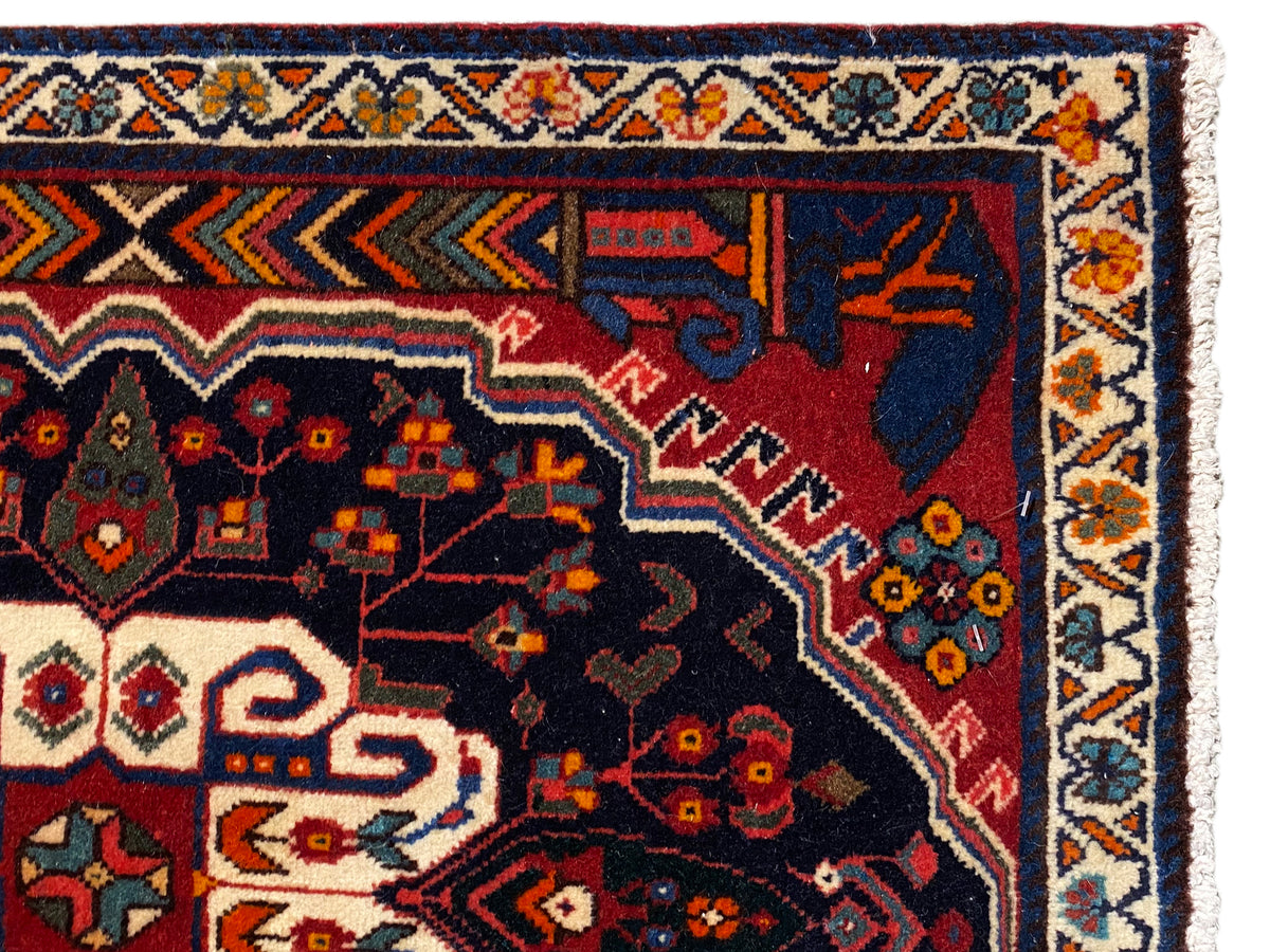 Primer plano de una cenefa de alfombra Poshti con ornamentos coloridos y un campo interior oscuro