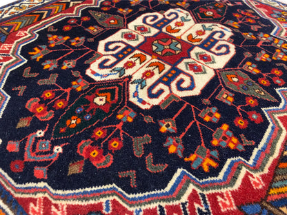 Detalle de la alfombra Poshti: patrón central blanco sobre fondo azul oscuro