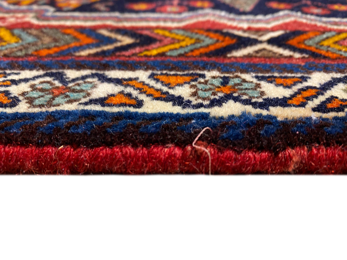 Primer plano del borde de la alfombra Poshti, con pelo denso y ribete rojo