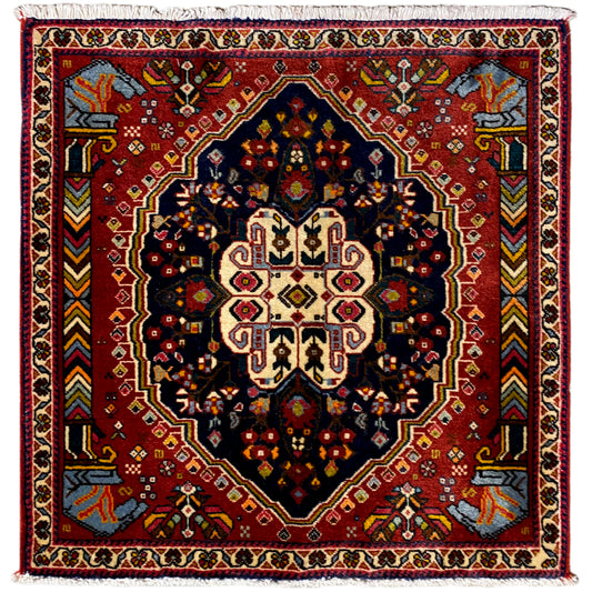 Alfombra Poshti con fondo rojo, patrón de octágonos azul oscuro y borde de cenefa blanco