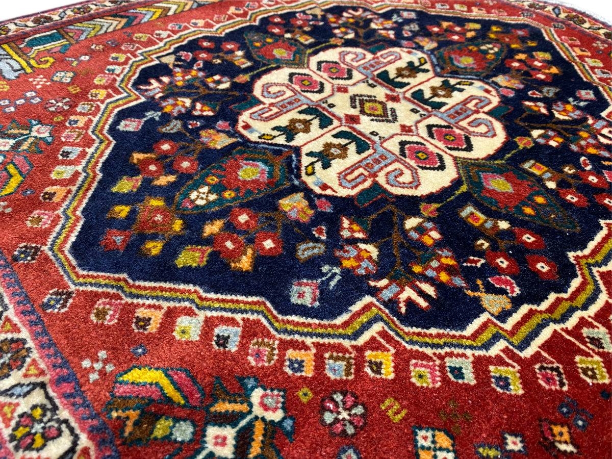Detalle de alfombra Poshti: motivo de cruz central con coloridos ornamentos decorativos