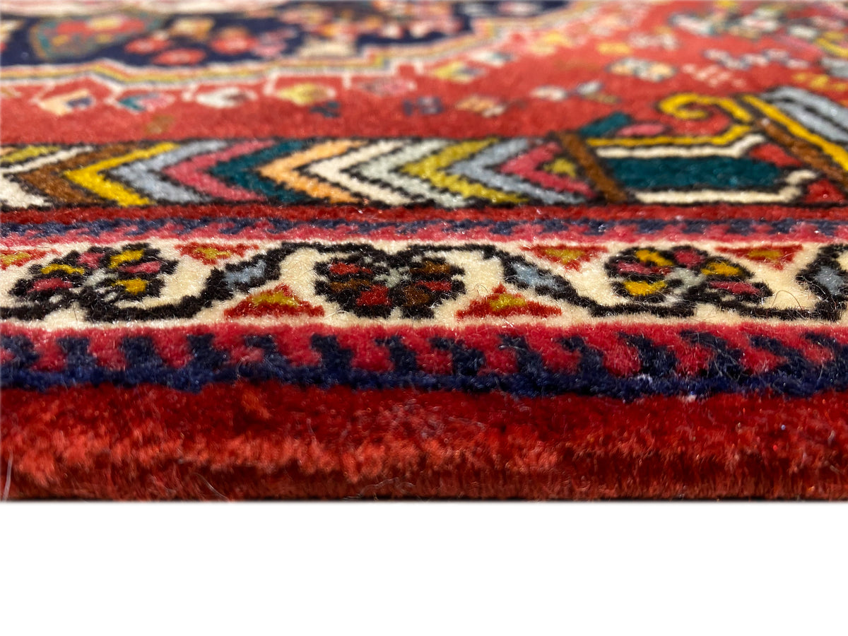 Detalle del borde de la alfombra Poshti con flecos rojos y azules y diseños tejidos