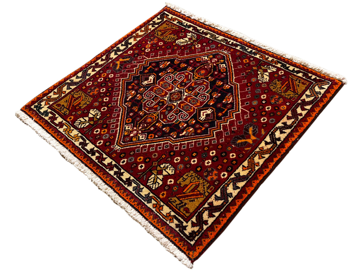 Alfombra Poshti de 60x60 cm, patrón cuadrado en rojo con motivo central amarillo anaranjado