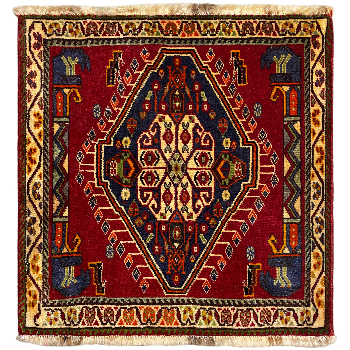Alfombra Poshti (59×61 cm) con diseño geométrico rojo, cenefas multicolores y flecos