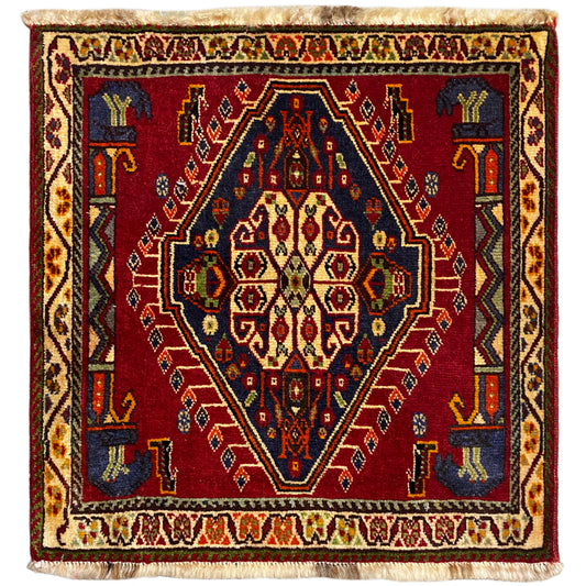 Alfombra Poshti (59×61 cm) con diseño geométrico rojo, cenefas multicolores y flecos