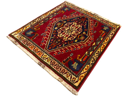 Alfombra Poshti (59×61 cm) cuadrada, con estampado rojo, bordes oscuros y flecos