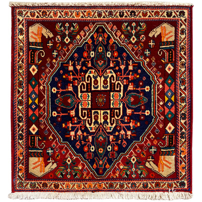 Alfombra Poshti de 64x64 cm, cuadrada, burdeos con ornamentación azul y flecos